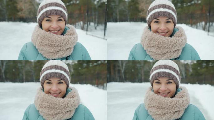 冬天穿着冬装站在公园门口的迷人年轻女士的慢动作肖像