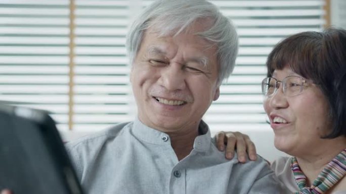 坦率的亚洲老退休夫妇使用平板电脑在网上或金融支付转账，并以快乐和积极的态度阅读文字，微笑或大笑。具有