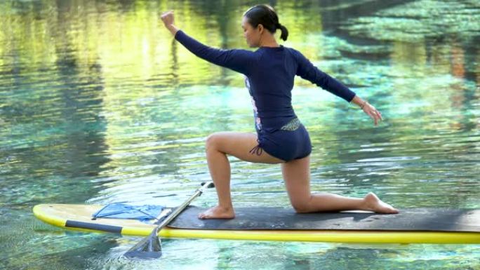 泰国女子在桨板上做瑜伽，战士姿势