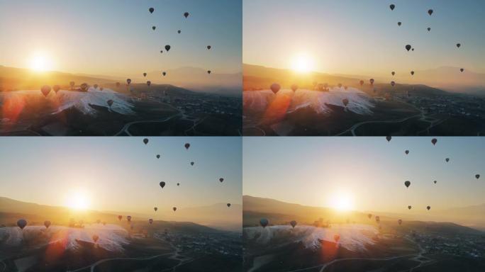 热气球在棉花堡山谷上空飞行，对抗山上升起的太阳。空中无人机视频