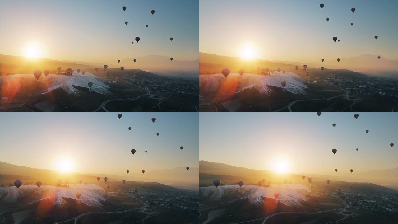 热气球在棉花堡山谷上空飞行，对抗山上升起的太阳。空中无人机视频