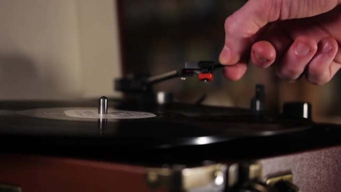 用手将电唱机的针放在旋转的黑胶唱片上。