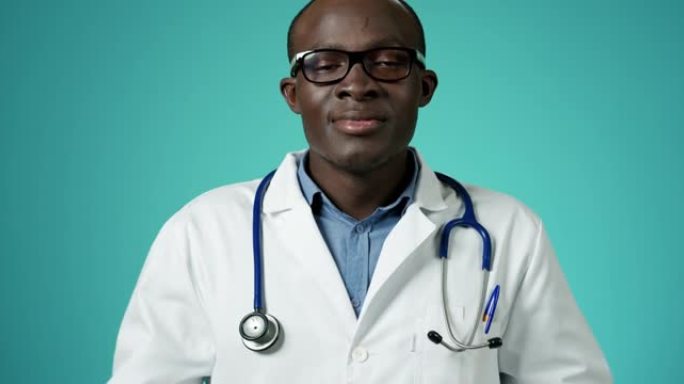 英俊的非洲裔美国医生摘下医用口罩，深呼吸，对着镜头慢动作微笑。看起来快乐和自由。特写医务人员脸部肖像
