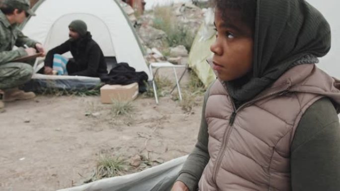 无家可归的女孩，拿着一罐食物坐在帐篷里