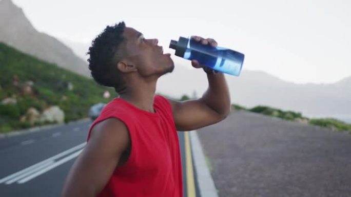 非裔美国男子站在马路上喝水