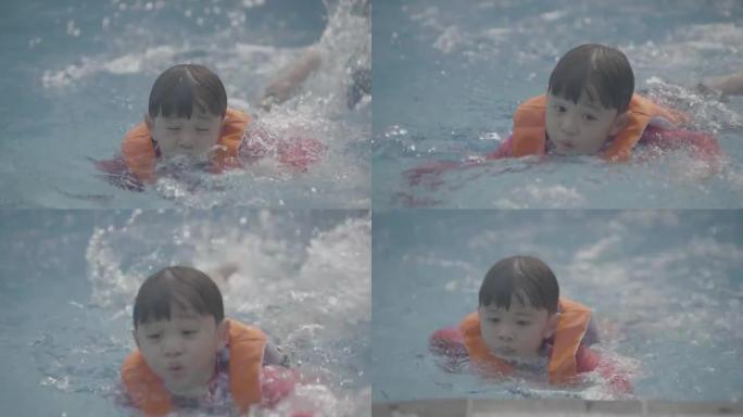 游泳池里穿着救生衣的亚洲小男孩