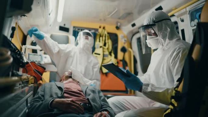 护理人员穿着工作服，使用平板电脑检查受伤患者在去医院的途中的诊断。紧急医疗护理助理将通风面罩放在救护