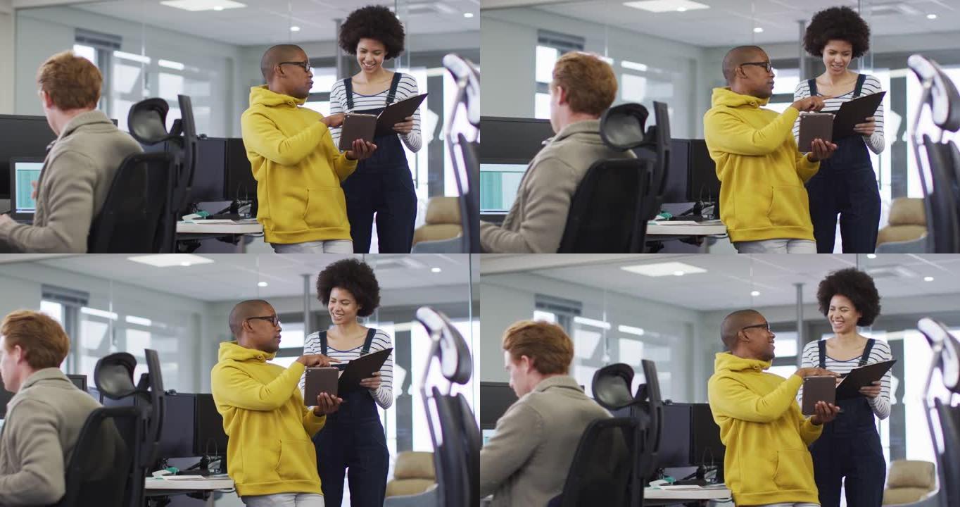 在办公室使用平板电脑和讨论文书工作时，面带微笑的男女商业同事