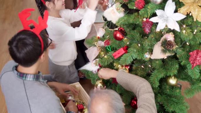 4K UHD高角度视图手持多代亚洲快乐家庭装饰圣诞树与装饰品一起为节日快乐冬天做准备。