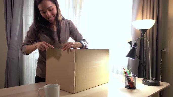 亚洲女人收到包裹和打开箱子在家很开心