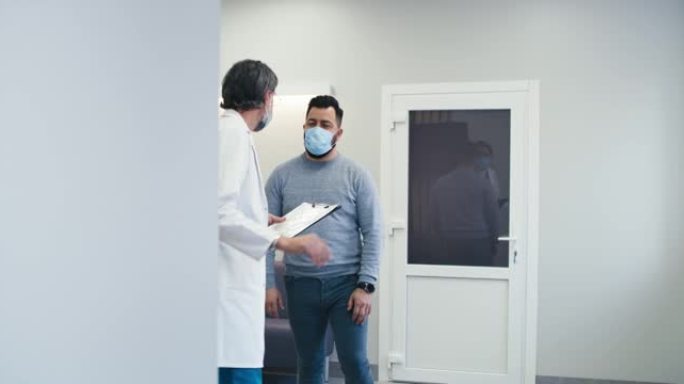 男医生在医院走廊与患者交谈
