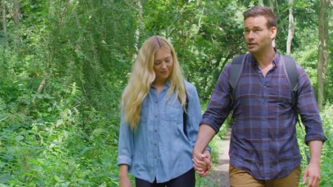 一对相爱的夫妇在乡下牵着手一起沿着森林徒步旅行