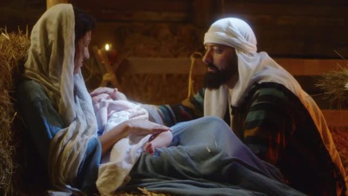玛丽和约瑟夫带着婴儿耶稣在昏暗的谷仓里休息