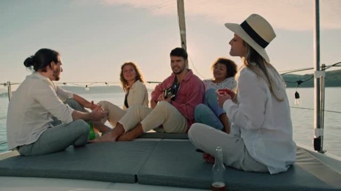 SLO MO一群朋友在日落时在船上的甲板上弹吉他