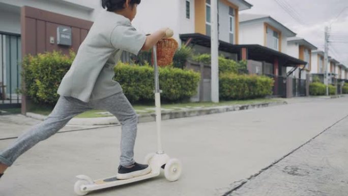 快乐的小男孩在城市骑踏板车。