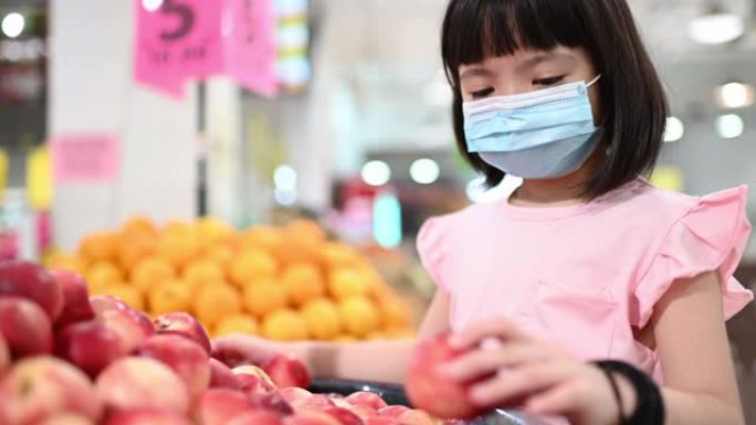 一个亚洲的中国女孩在超市买水果在周末看水蜜桃