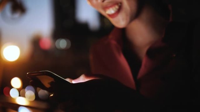 在夜城的街道上散步时，使用手机的迷人女人的特写镜头