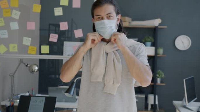 大流行期间，年轻企业家在办公室戴上医用口罩的慢动作肖像