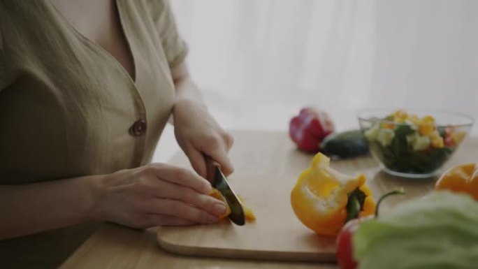 女孩在厨房用刀手工准备食物制作蔬菜沙拉切胡椒粉的特写