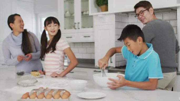 快乐的亚洲父母与儿子和女儿一起在厨房里烘烤