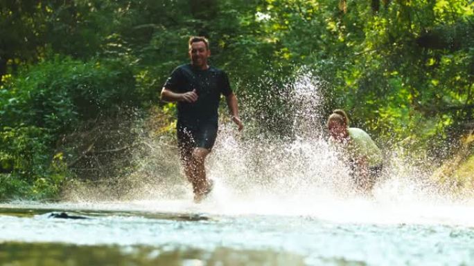 超级SLO MO夫妇在森林里跑过小溪时玩得开心