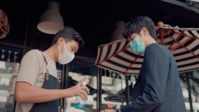 戴着外科口罩微笑的亚洲员工为客户做温度检查和服务酒精凝胶。