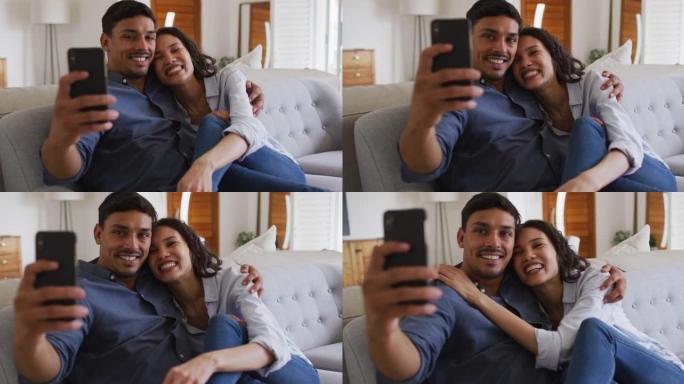 快乐的西班牙裔夫妇在客厅沙发上拥抱自拍