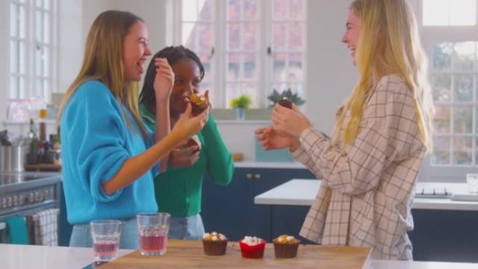 一群多元文化的少女朋友在家里的厨房里吃慢动作拍摄的纸杯蛋糕