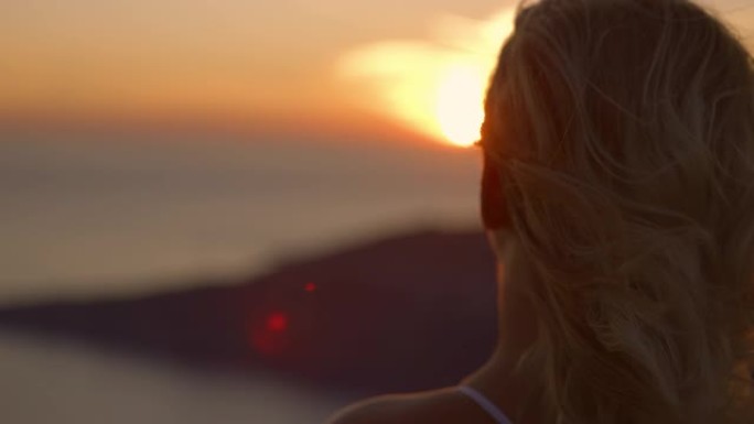 懒散的女人，头发飞舞，享受着令人惊叹的海景和美丽的日落