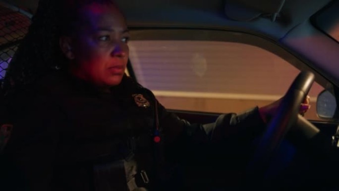 在警察交通巡逻巡逻车内:值班的黑人女警察，从中心调度员接收紧急扫描仪无线电呼叫，响应，打开警报器，开