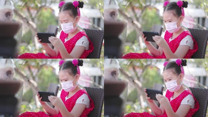 带防护口罩的亚洲小女孩打算看手机
