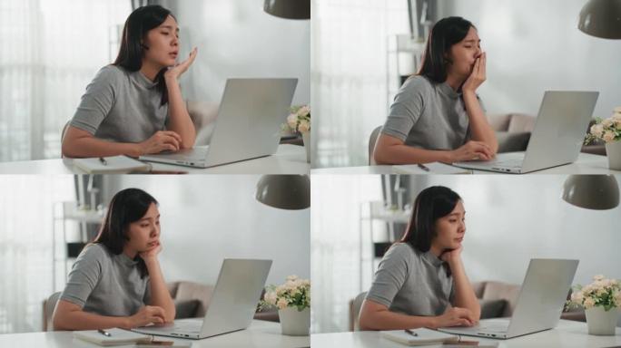 亚洲妇女在家里使用笔记本电脑而苦苦挣扎