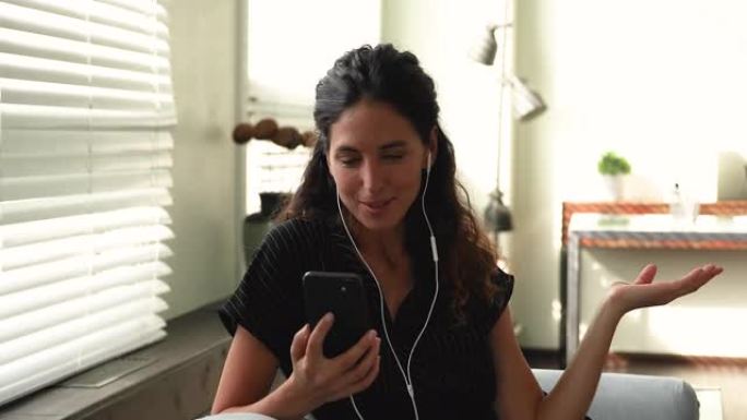 女人戴有线耳机使用智能手机进行视频通话