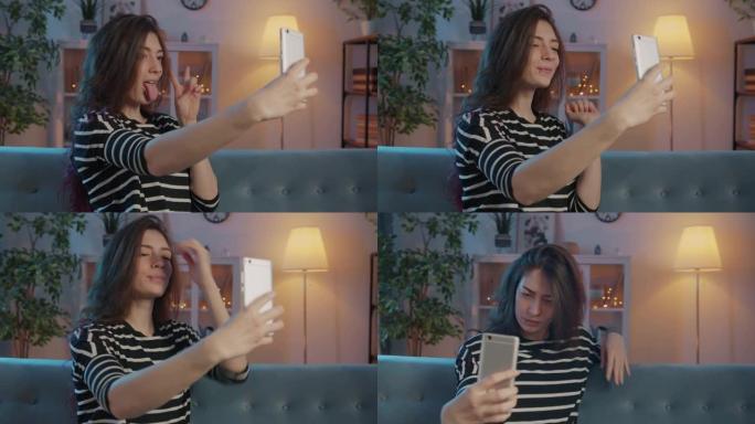 漂亮的年轻女士在照明公寓中使用智能手机相机自拍