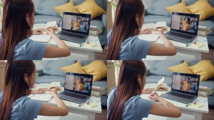 年轻的亚洲女孩与休闲使用电脑笔记本电脑视频通话在线学习与老师在家里写讲座笔记本客厅。隔离教育在线电子