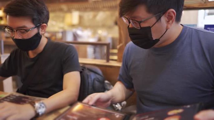 两名男子在日本餐厅订购，戴着口罩，新常态