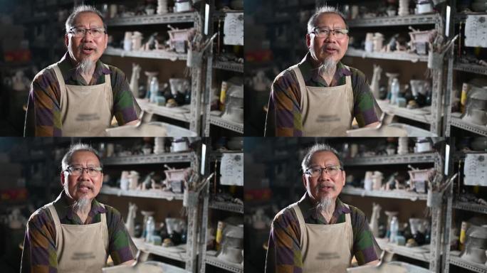 亚洲中国高级男子粘土艺术家在他的工作室里说话和看着相机