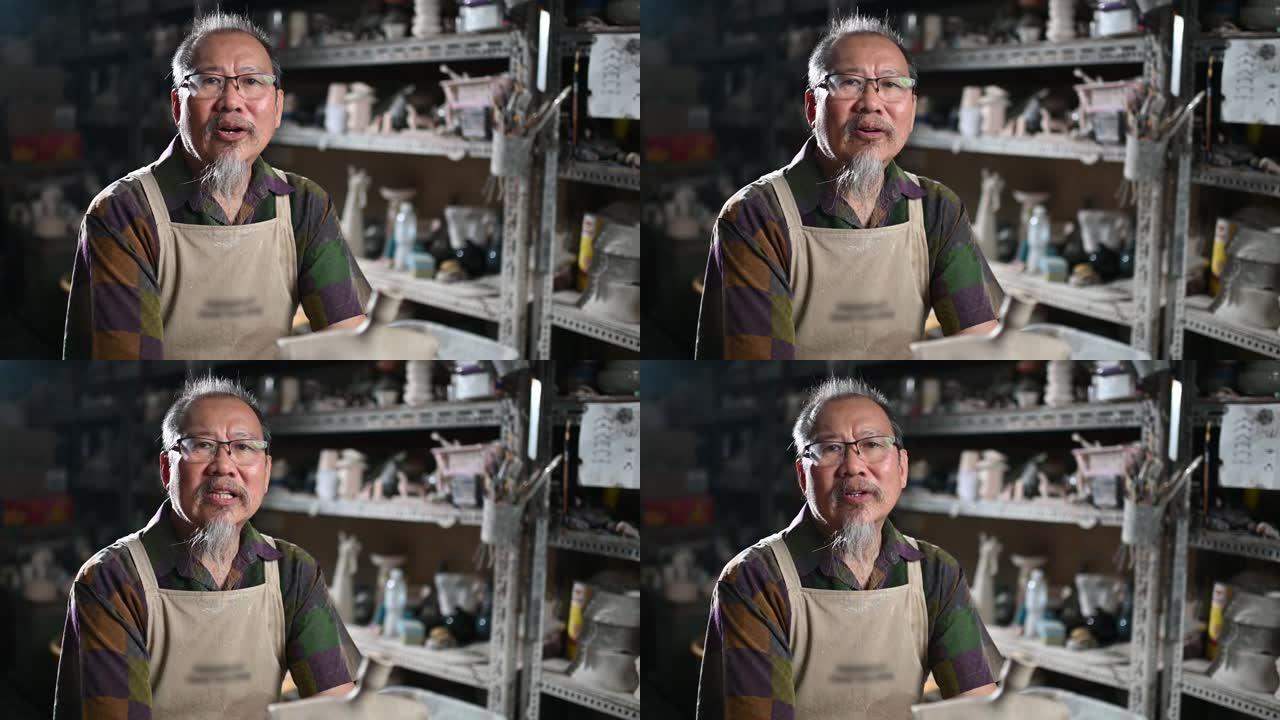 亚洲中国高级男子粘土艺术家在他的工作室里说话和看着相机
