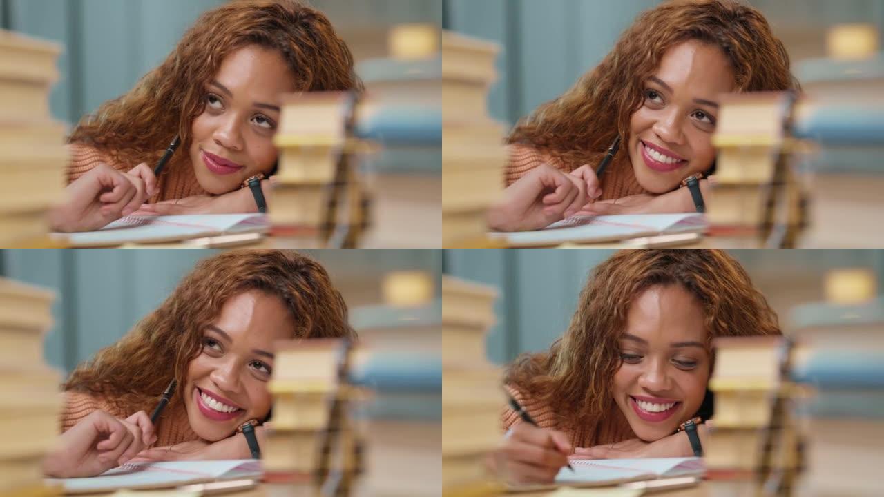 年轻的创意女作家微笑着思考，并在桌上的笔记本上写想法。快乐的大学生在为大学课程学习的同时用钢笔写文章