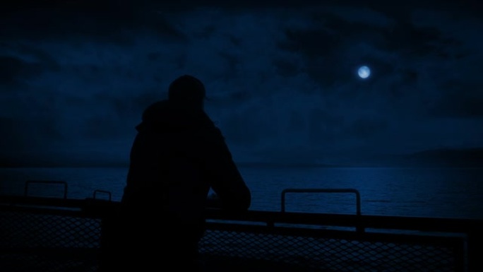 男人在月光下从船后看