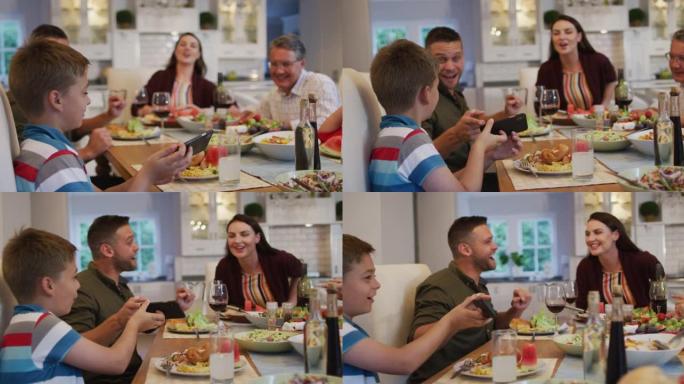 快乐的高加索孙子在家庭用餐时与父母和祖父在餐桌上自拍