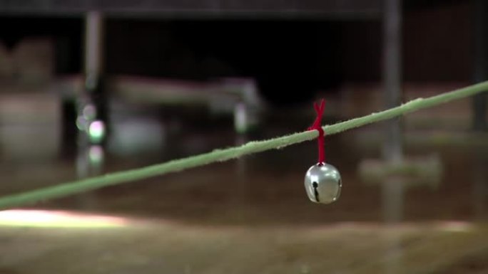 在阿根廷的一所盲人或视障儿童学校中，挂在用作游戏网的绳子上的铁叮当铃。特写。