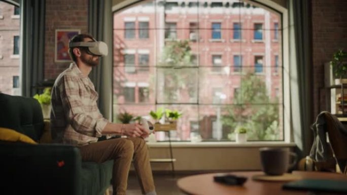 成年大胡子男性在家中使用虚拟现实耳机和控制器。有创造力的人坐在客厅的沙发上，玩VR视频游戏或使用特殊