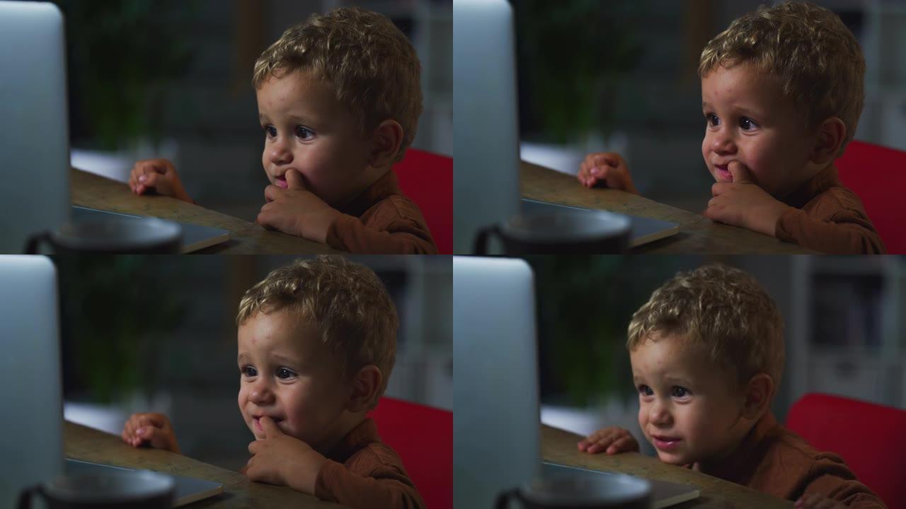 小可爱男孩的肖像使用笔记本电脑，通过互联网上的教育内容学习新单词。他快乐而专注。男性幼儿喜欢他最喜欢