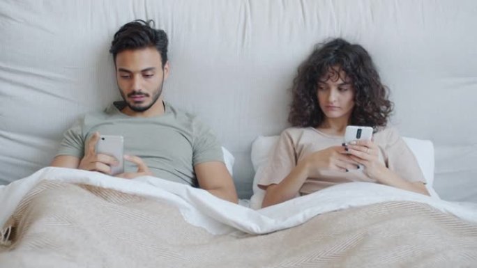 年轻女子在床上使用智能手机时殴打阿拉伯丈夫