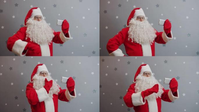 穿着圣诞老人服装的男子拿着智能手机触摸屏在灰色背景上自拍