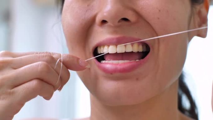 无法辨认的年轻女子在家里的浴室里用牙线洁牙