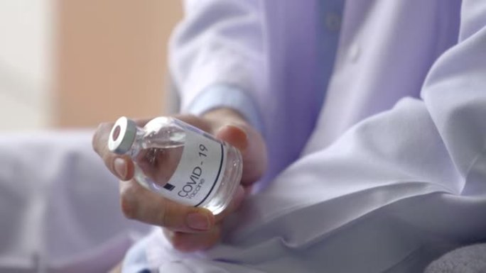 年轻的男性医生拿着一个新型冠状病毒肺炎的疫苗瓶，它传达了希望有一个疫苗来帮助预防流行病。