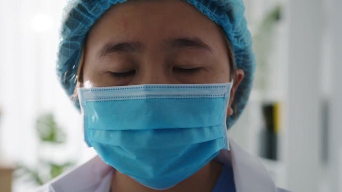 年轻的亚洲女士医生或护士工人外科医生准备手术和疲倦睁开眼睛，看着健康医院的相机。
