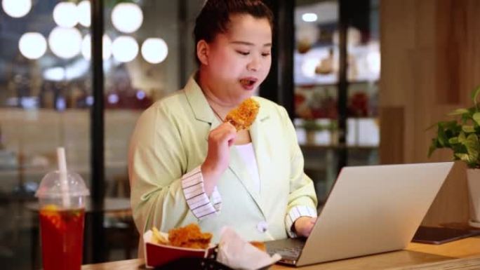 女商人在使用笔记本电脑时吃炸鸡